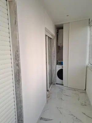 a hallway with a white wall and a microwave at Apartamento T1 a 10m da praia Quarteira in Quarteira