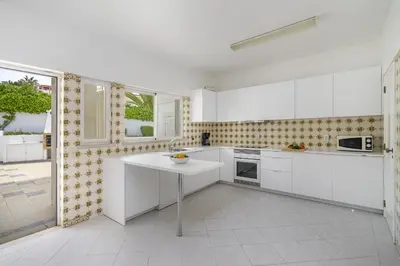 a kitchen with white cabinets and a table in it at Villa Sitambo- Pool & Sea View in Albufeira