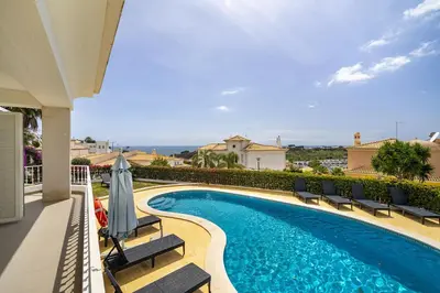 a swimming pool with chairs and an umbrella on a balcony at Villa Sitambo- Pool & Sea View in Albufeira