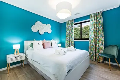 a blue bedroom with a bed and a chair at Apartamento T3 Praia da Falésia - PINE SUN PARK in Albufeira