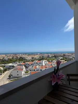 a flower on a balcony with a view of a city at Albufeira Cozy Sea View with Balcony & Resort Access in Albufeira
