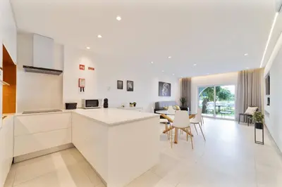 a kitchen and dining room with white cabinets and a table at Saro Apartment by HelloVacations in Albufeira