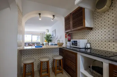 a kitchen with two bar stools and a microwave at Apartamento de 2 quartos Hibiscus 40A na Praia de Sao Rafael - Albufeira, Algarve in Albufeira