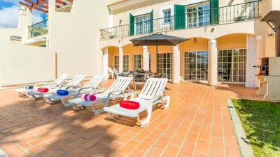 a group of chairs and an umbrella on a patio at Vilamoura - VILLA LIMONI in Vilamoura