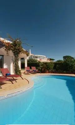 a swimming pool with chairs and a house at Villa Vilamoura, piscina privada in Quarteira