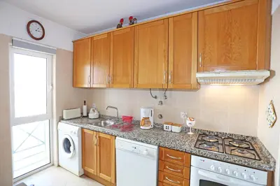a kitchen with wooden cabinets and a washer and dryer at A32 - Lancemar Flat in Albufeira in Albufeira