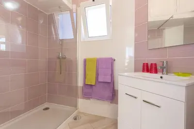 a bathroom with a sink and a shower with purple and yellow towels at Toiago in Vilamoura