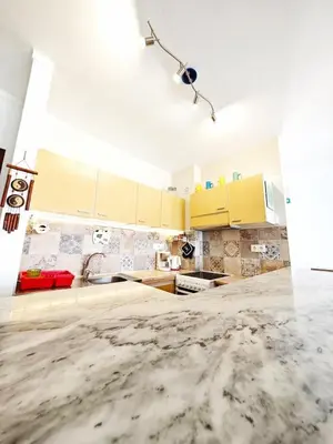 a kitchen with yellow cabinets and a marble floor at Blife Paulya private apartment in Faro
