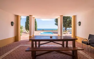 a living room with a table and a pool at Casa da Vigia - waking up in front of the sea in Albufeira