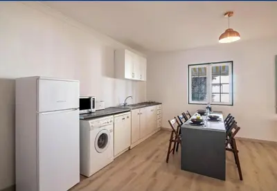 a kitchen with a white refrigerator and a table with chairs at Casa da Vigia - waking up in front of the sea in Albufeira