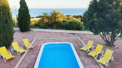 a swimming pool with yellow chairs and a pool table at Casa da Vigia - waking up in front of the sea in Albufeira
