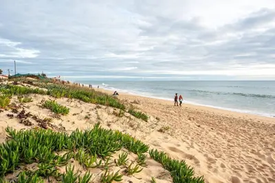 a beach with people walking on the sand and the ocean at Blife Benya private apartment in Faro