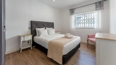 a bedroom with a bed and a chair and a window at Cozy 2BR near Oura Beach by LovelyStay in Albufeira