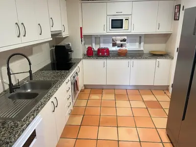 a kitchen with white cabinets and a tile floor at SomeSunnyDay Vila Sol Village in Quarteira