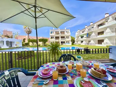 a table with plates of food and an umbrella at Vilamoura Golf Apartment 2 With Pool by Homing in Vilamoura