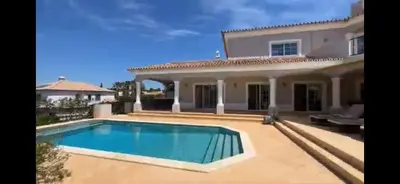 a villa with a swimming pool in front of a house at The Beverly Vilamoura in Quarteira