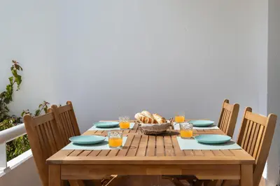 a wooden table with a basket of bread and glasses of orange juice at BmyGuest - Quinta do Lago Cosy Apartment in Quinta do Lago