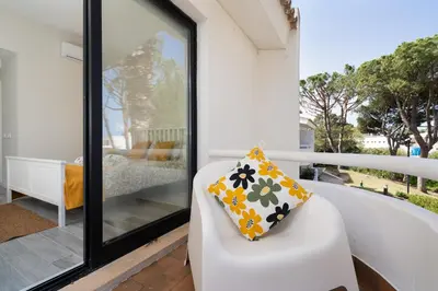 a white chair with a pillow on a balcony at BmyGuest - Quinta do Lago Cosy Apartment in Quinta do Lago