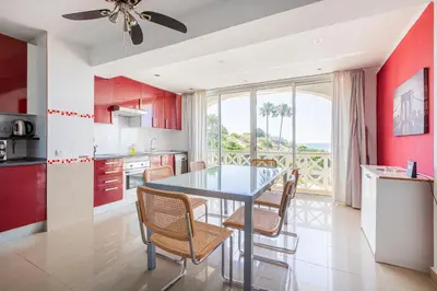 a kitchen with red cabinets and a table with chairs at Beachfront apartment Praia dos Aveiros in Albufeira