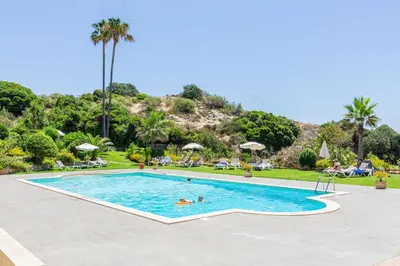 a swimming pool with two people in a resort at Beachfront apartment Praia dos Aveiros in Albufeira