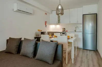 a living room with a couch and a table and a kitchen at Apartamento Condomínio Montechoro by CM Properties in Albufeira