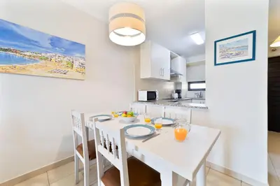 a white kitchen with a white table and chairs at Passport Beach - 201 by HelloVacations in Albufeira
