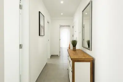 a hallway with white walls and a table and a mirror at Flores 2Bedroom Apartment - Sea view Quarteira in Quarteira