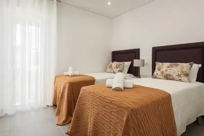 two beds in a room with white walls and windows at Flores 2Bedroom Apartment - Sea view Quarteira in Quarteira