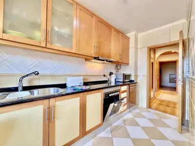 a kitchen with wooden cabinets and a sink at Vilamoura Lovely Beach Stay With Pool by Homing in Vilamoura