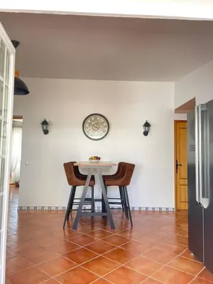 a table and chairs in a room with a clock on the wall at Quinta da Calma with pool and BBQ in Boliqueime