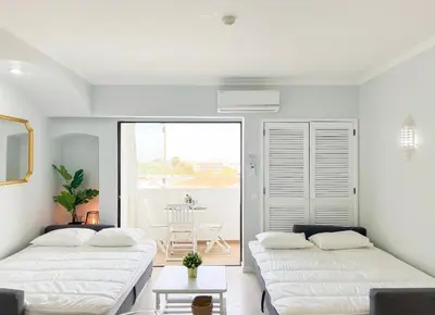 two beds in a white room with a table at Sea View Apartment Albufeira in Albufeira