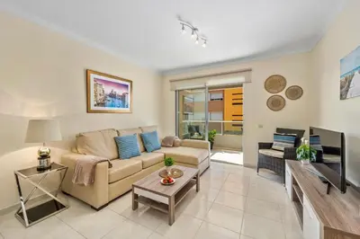 a living room with a couch and a tv at Pool with Beach 10' Away - Comfort and Tranquility in Quarteira