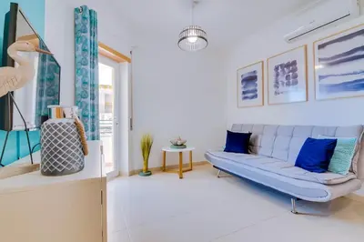a living room with a blue couch and a window at Falesia beach Pool quiet side by Enjoyyourstay in Albufeira