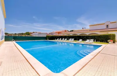 a large swimming pool with chairs and a building at Falesia beach Pool quiet side by Enjoyyourstay in Albufeira