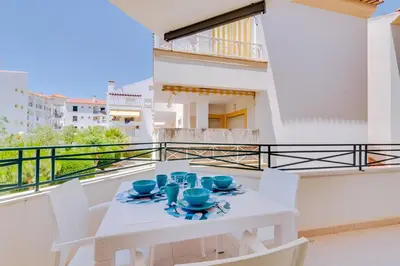 a white table and chairs on a balcony at Falesia beach Pool quiet side by Enjoyyourstay in Albufeira