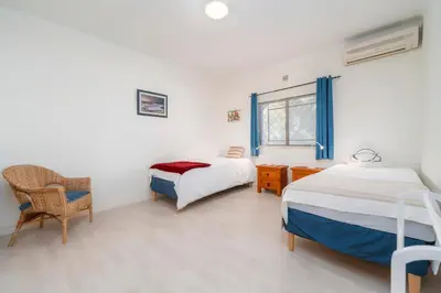 a bedroom with two beds and a chair and a window at Villa 4 Quartos, Piscina, BBQ Snooker, Prestige For Home in Quarteira