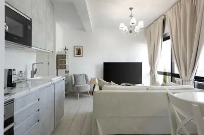 a white living room with a couch and a tv at Vilamoura Retreat - Sunset View by HD in Vilamoura