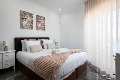 a bedroom with a bed with white sheets and a window at Espadarte - Sea view by HD in Quarteira