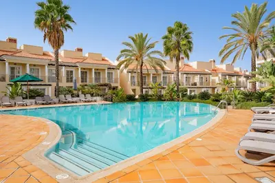 a large swimming pool with chairs and palm trees at Palmyra Apartments in Vilamoura in Vilamoura
