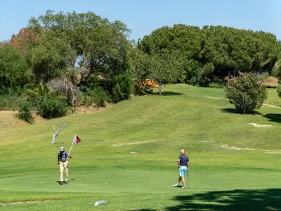 two men playing golf on a golf course at Luxury Beach House Apartment - Golf & Tennis Court & Pool View in Albufeira