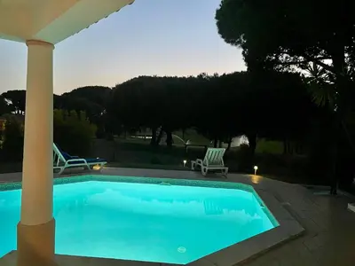 a swimming pool in a yard with two chairs at Villa Maria in Vilamoura
