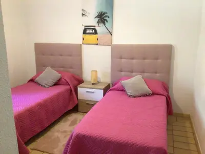 a bedroom with two beds with pink covers and a yellow car on the wall at 2 Bedroom Townhouse, Vale de Parra in Guia