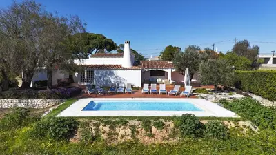 a villa with a swimming pool in front of a house at Casa da Colina in Albufeira