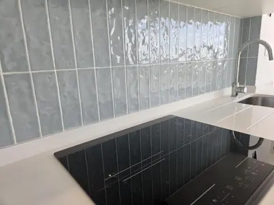 a kitchen with a sink and a black tile wall at Apartamento moderno com vista para o mar em Faro in Faro