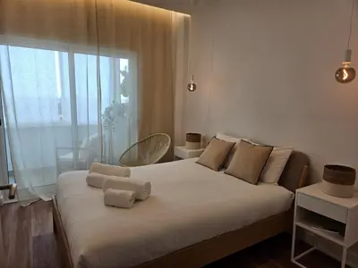 a bedroom with a bed with white sheets and a window at Apartamento moderno com vista para o mar em Faro in Faro