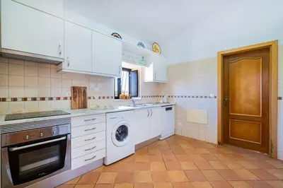 a kitchen with white appliances and a washer and dryer at Quinta da Bisa - Casa das Pedrinhas in Algoz