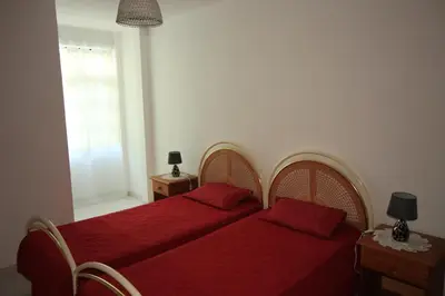 a bedroom with two beds with red sheets and a window at Modern Apartment in Albufeira in Albufeira