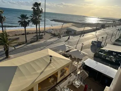 a view of a beach with a building and the ocean at Adrimar - Beachfront Sea View 2BR Apartment in a prime location in Quarteira