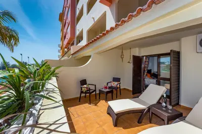 a balcony of a house with chairs and tables at Clementina Apartment in Albufeira