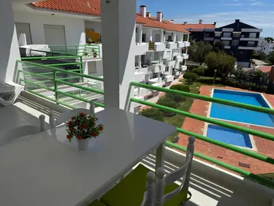 a balcony with a table and chairs and a swimming pool at Jardim Santa Eulália By Albufeira Rental in Albufeira